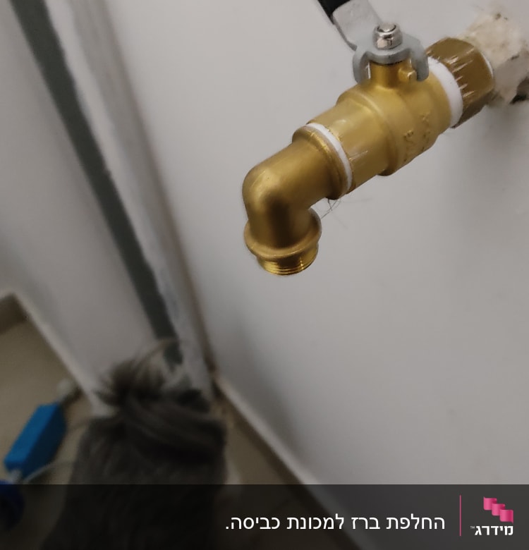 ברז פליז עם ידית שחורה על קיר לבן